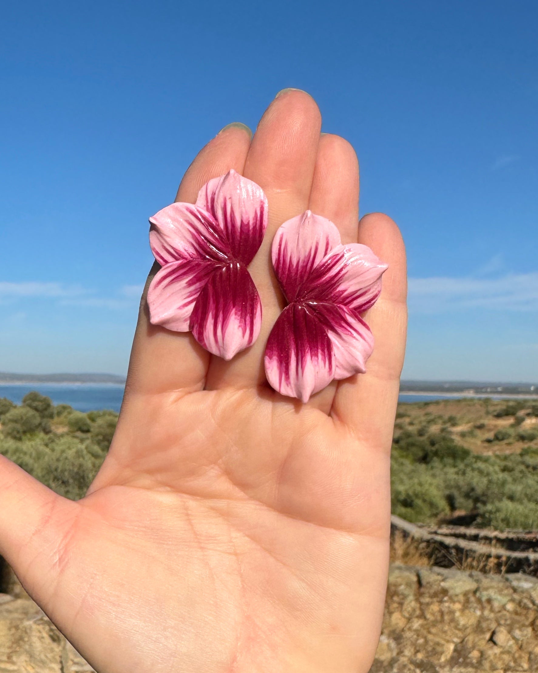 Pendientes Berlanga en detalle diseño de media flor en tonos burdeos y rosa