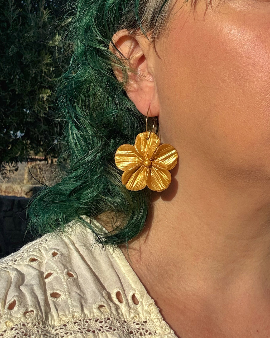 Pendientes Granadilla dorado sobre modelo flor cinco pétalos hechos a mano.