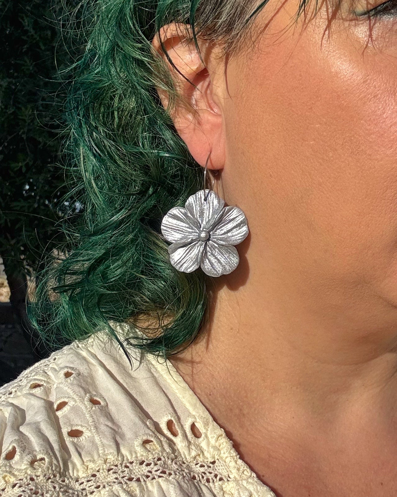 Pendientes Granadilla en plateado sobre modelo diseño de flor de inco pétalos.