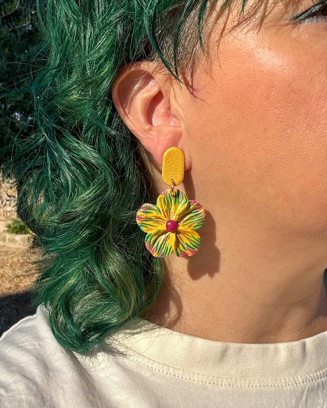 Pendientes Granadilla diseño floral con botón sobre modelo.