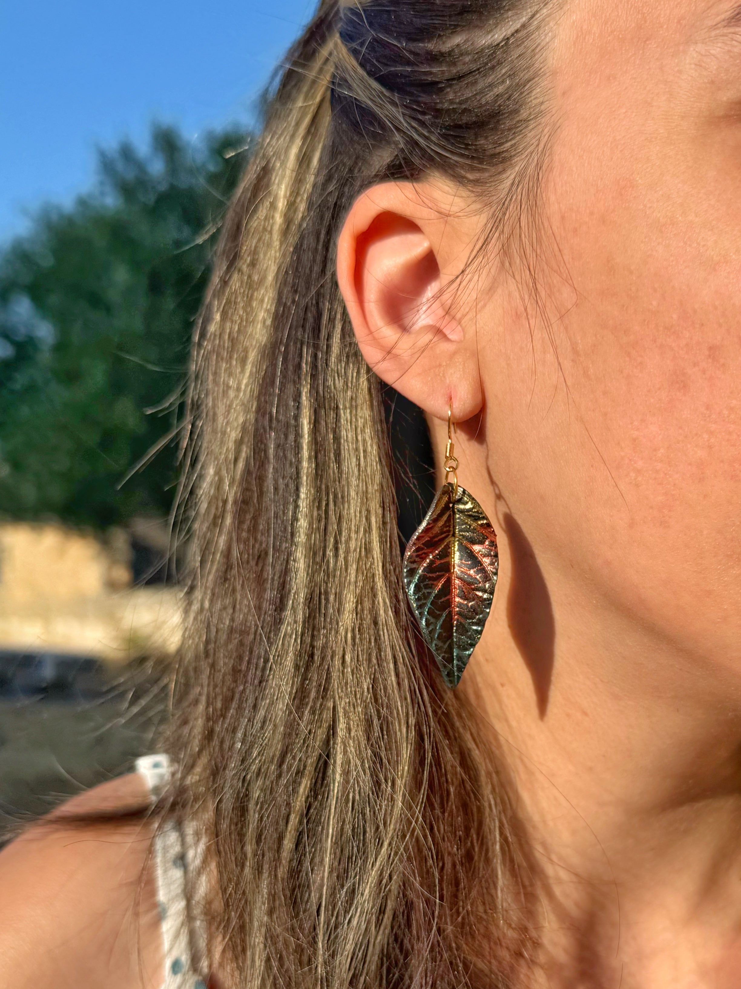 Pendientes Hoja Atardecer en tonos cálidos sobre modelo.