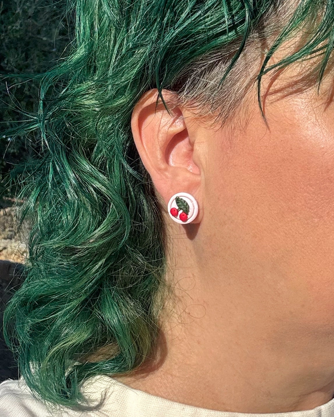 Pendientes ini de botón de cerzas mini en modelo.
