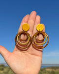 Detalle de los pendientes Olivenza hechos a mano en madera y arcilla polimerica en el tono dorado