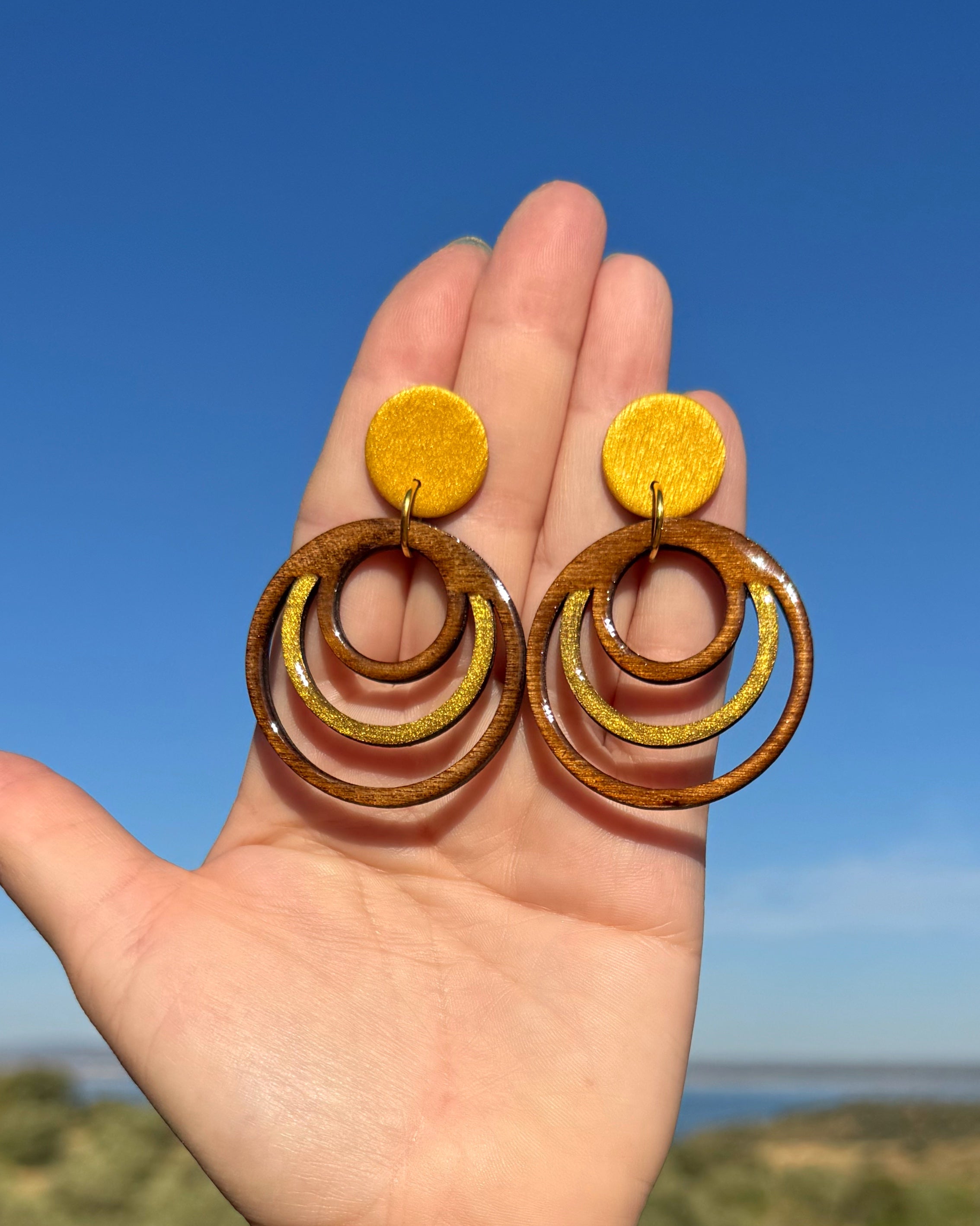 Detalle de los pendientes Olivenza hechos a mano en madera y arcilla polimerica en el tono dorado